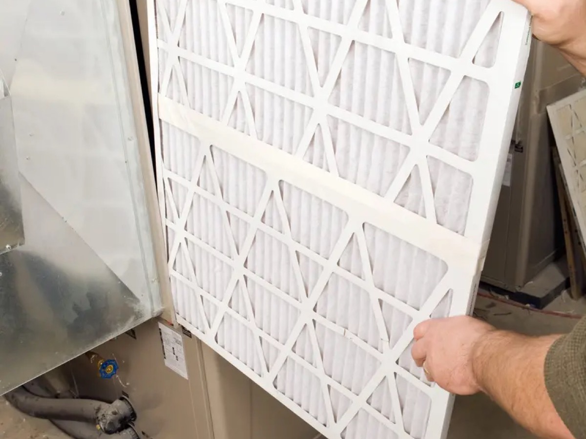 Technician replacing a residential furnace air filter